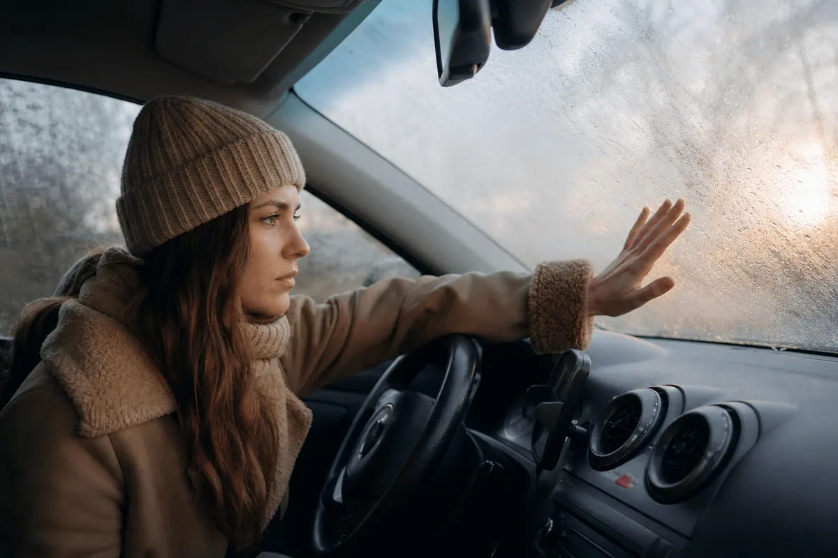 Pare-brise de voiture embué de l'intérieur un matin d'hiver, vu depuis l'habitacle
